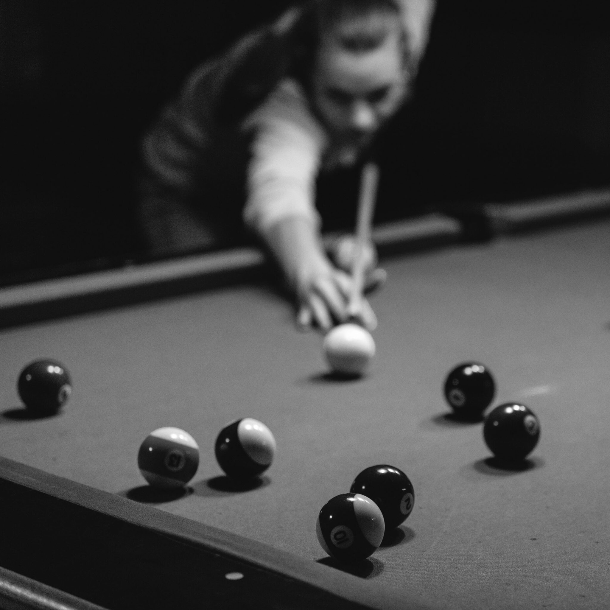 Pool (billiard) table with balls and unrecognizable woman taking a shot
