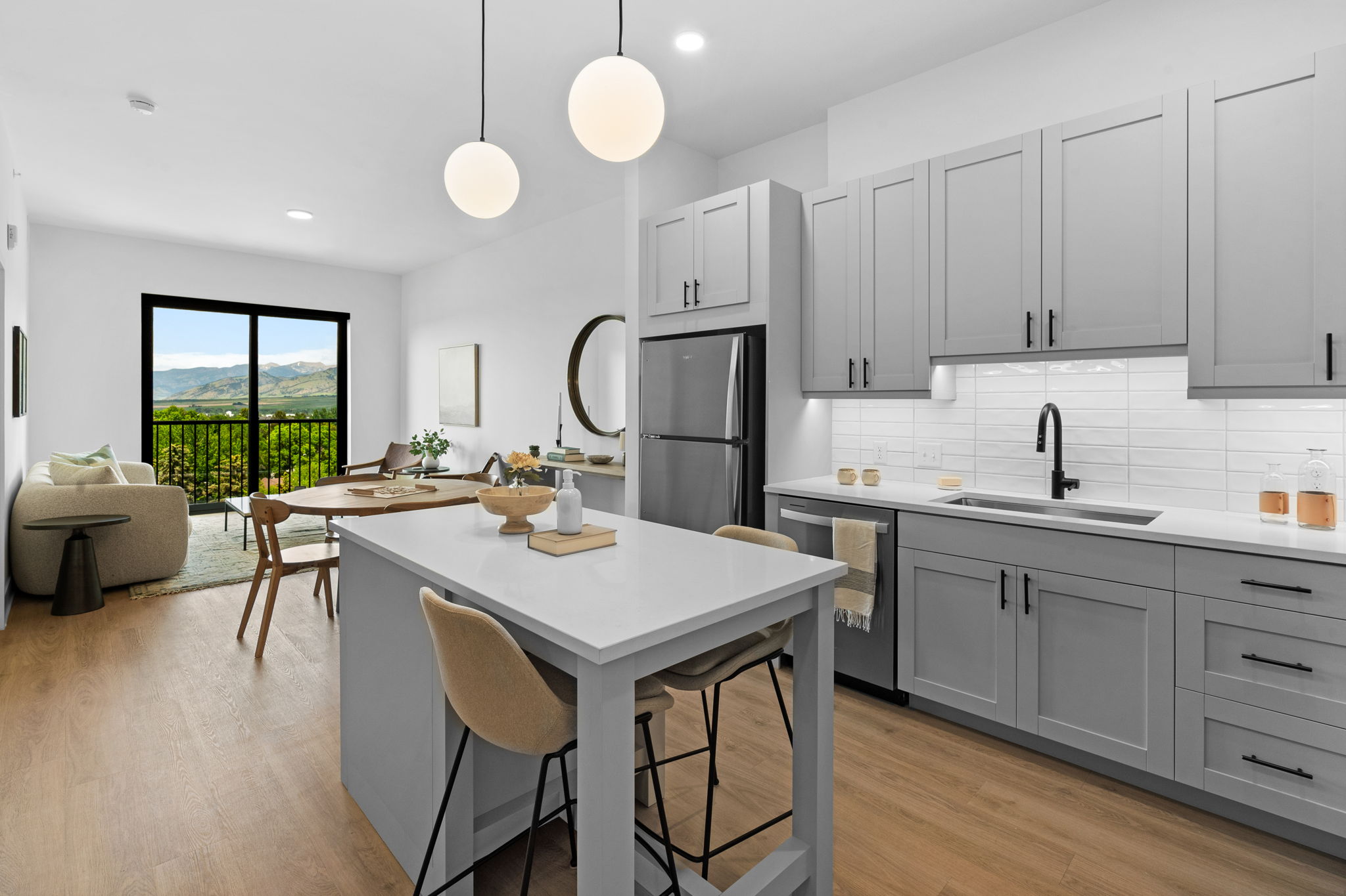 Kitchen island with light grey cabinets, white quartz countertops, and black finishes